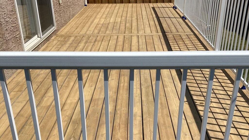 Pools & Decks 4 Wood deck, midrange shot, bright with white railing and shadow lines.